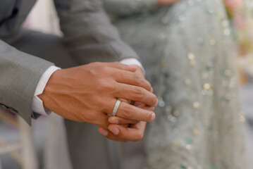 Close up of the groom wearing his wedding ring.