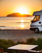 © anandart - Table background with a wooden board and sunny beach and ocean and a camper van