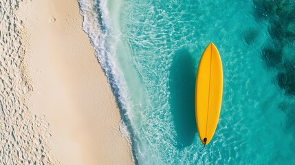 Poster - Yellow surfboard on pristine sandy beach with clear turquoise waters, aerial view. Tropical vacation and adventure concept