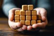 © Worrapol - Building a Foundation: Hands carefully hold a wooden block tower, symbolizing growth, stability, and the process of building something great. Each block represents a step towards a strong future.