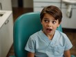 © Kasper - Top view of a young boy in a dental chair looking surprised at a dentist.