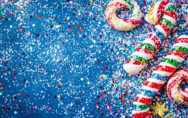 Colorful candy canes and confetti on a snowy blue background, evoking festive winter celebrations