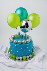 Wall Mural - A delightful blue birthday cake with silver decorations and green balloons in a minimalistic white background.