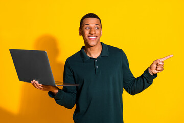 Wall Mural - Photo portrait of handsome young guy netbook point look empty space dressed stylish green garment isolated on yellow color background