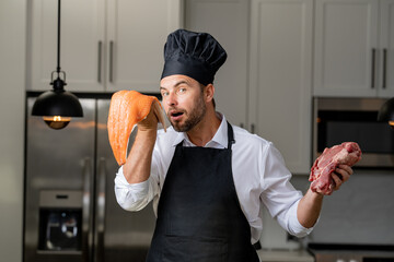 a male chef holding a steak and fish in the kitchen . chef preparing food, close-up of chef cooking meat in the kitchen, chef cooking delicious foods in the kitchen, man in the kitchen, cooking man 