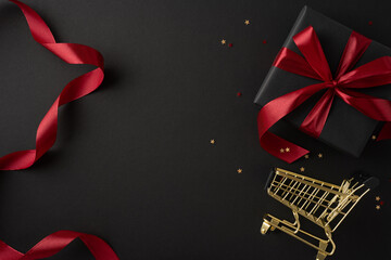 Wall Mural - A festive Black Friday shopping scene with a gold shopping cart, black gift box with red ribbon, and decorative stars on a dark background