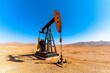 © Sanchai - Oil pumpjack in the middle of a serene desert landscape, with minimal vegetation and clear blue skies