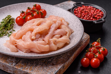 Raw chicken fillet cut into strips with spices and herbs