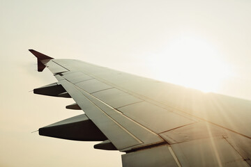 Flight, plane and wing on sky background for holiday, travel or vacation to overseas destination. flare, sunshine and transport with aircraft flying on mockup space for international or global trip