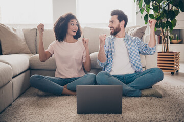 Sticker - Full size photo of two nice young partners sit floor laptop raise fists weekend modern apartment indoors