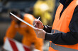 © zphoto83 - Worker in safety vest takes notes while overseeing construction site operations during daylight hours