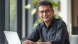 © Yevhen - Mature indian or latin businessman working on laptop in modern office, smiling and focused
