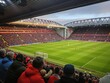 © Vadym - Crowd of people gathered at Anfield Stadium watching a football game. Green grass and grandstands fill the frame. Excited fans cheering and waving their arms in the stands. Sports event atmosphere.