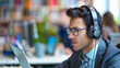 © Zhongyuan Chen - A man wearing noise-canceling headphones appears focused and comfortable, undisturbed by the busy, blurred office environment around him.