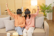 © Pichsakul - Lifestyle at home concept, LGBT lesbian couple in VR goggles to playing game and making win gesture