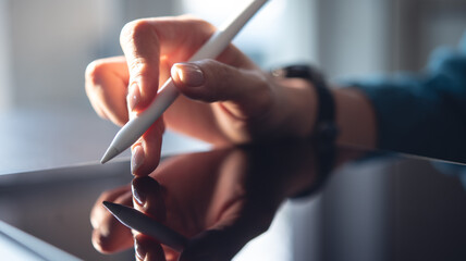 Wall Mural - Closeup, woman hand with stylus pen using digital tablet, finger touching on tablet screen with sunlight, backlit. Surfing the net, internet networking