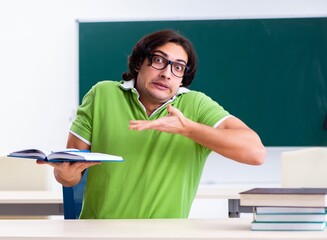 Canvas Print - Young male student in front of green board