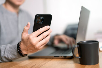 Business man using mobile smart phone and online working on laptop computer, surfing the internet, searching the information at home office.