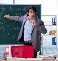 Wall Mural - Young handsome math teacher in classroom