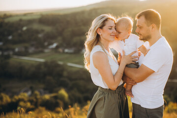 Happy Family Embracing Outdoors in Golden Sunset on Scenic Hilltop