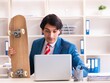 © Elnur - Young handsome businessman with longboard in the office