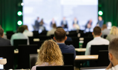 Wall Mural - rear view of the audience at a business conference meeting event listening to the speakers speech