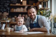 © MarGa - Smiling white father in an apron sitting at a table with his baby girl wearing a pink headband in a cozy cafe, concept of family bonding and parent-child time, small business theme