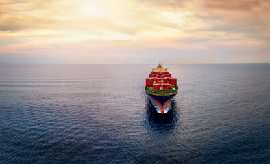 Aerial front view of a big cargo container carrier ship sailing over the ocean during sunset time with copy space