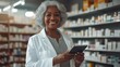 © Yulia - Senior african american old woman pharmacist working in pharmacy holding digital tablet