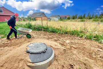 Installation of sewer system for private house in suburbs, builder delivers sand in wheelbarrow.