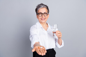 Wall Mural - Photo portrait of attractive pensioner woman take meds drink glass water dressed stylish formalwear isolated on gray color background