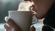 © Felippe Lopes - Woman inhales the steam from a cup of hot beverage.