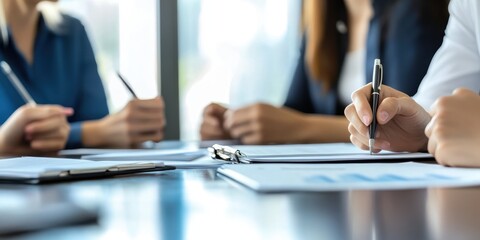 Close-up of professionals discussing documents during a meeting, focusing on hands and papers on a conference table.