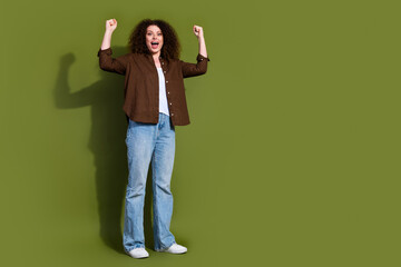 Wall Mural - Full size photo of pretty young woman raise fists empty space isolated on khaki color background