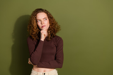 Wall Mural - Photo of doubtful unsure girl wear brown shirt arm chin looking empty space isolated green color background