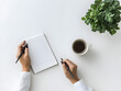 © Zape - Businesswoman sitting at a minimalist desk with a notebook and coffee.
