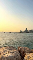 Wall Mural - Wooden passenger dhow passes by a hazy view of the Doha. Qatar skyline. in the Persian Gulf. Video 4k Ultra HD. High quality 4k footage