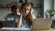 © alan - Woman overwhelmed with financial worries, working on laptop.