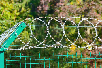 Barbed wire on top of a fence: a symbol of building barriers, protection against migration, and division in society.