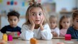 © Pinklife - A young girl with wide, surprised eyes sits among other children in a classroom, capturing a moment of surprise and curiosity in a playful, educational setting.