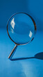© VERTEX SPACE - A magnifying glass rests on blue surface, showcasing its clear lens and metallic handle. light reflects beautifully, creating an intriguing visual effect