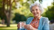 © Pinklife - An elderly woman with white hair and a warm smile sits outdoors, holding a glass of water in a garden, basking in the sunlight enjoying peaceful serenity.