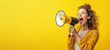 © Imagination Stock - Happy young woman in a yellow sweater, announcing sale offers through a megaphone, isolated on a yellow background with copy space. Screaming into the megaphone. Studio portrait.