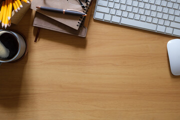 Wall Mural - Top view of wooden desk with a cup of coffee, notebooks and a computer keyboard. Copy space for text.