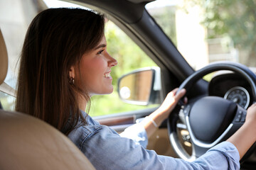 Wall Mural - Smiling woman holding steering wheel while driving car