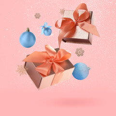 Poster - Gift boxes, Christmas balls and decorative snowflakes in air on pink background