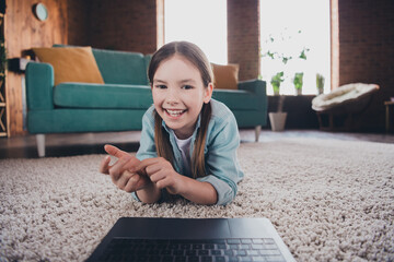 Canvas Print - Photo of lovely small girl lying floor chatting video call lesson laptop loft interior apartment indoors