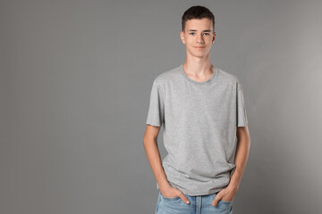 Wall Mural - Teenage boy wearing t-shirt on grey background, space for text