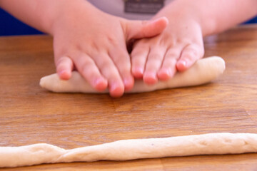 happy boy in the kitchen. Child roll out the dough with a rolling pin. Holiday and family leisure concept. Mother with child making biscuits on table. High quality photo