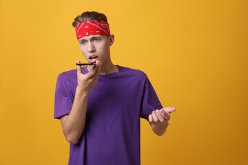 Poster - Young man recording voice message via smartphone on orange background